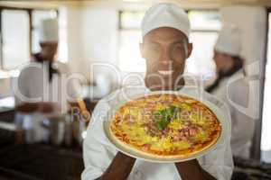 Portrait of smiling chef showing pizza