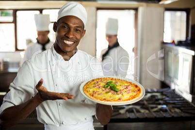 Portrait of smiling chef showing pizza
