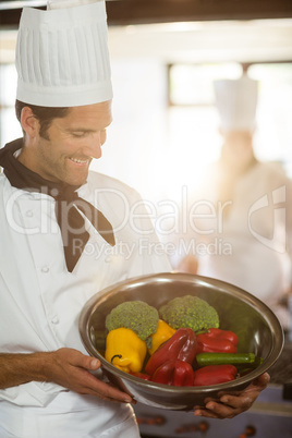 Smiling chef showing bowl of vegetable