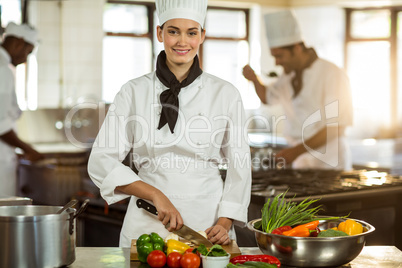 Portrait of female chef cutting vegetables