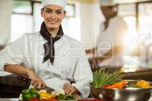 Portrait of female chef cutting vegetables