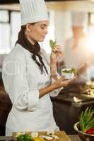 Young female chef smelling herb