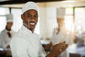 Portrait of smiling chef using digital tablet