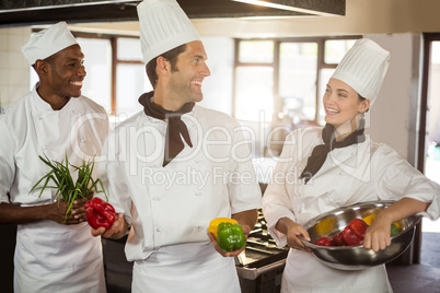 Smiling three chefs holding a vegetables