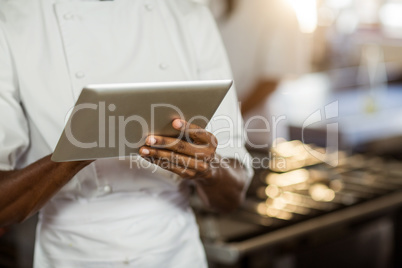 Mid section of chef using digital tablet