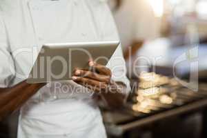 Mid section of chef using digital tablet