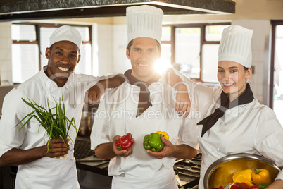 Portrait of three chefs holding a vegetables