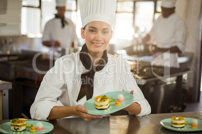 Portrait of female chef holding dessert plate