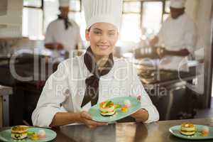 Portrait of female chef holding dessert plate