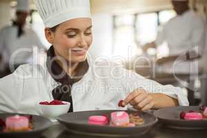 Smiling female chef finishing dessert plates