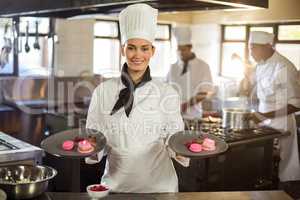 Portrait of smiling female chef presenting dessert plates