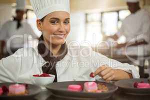 Portrait of smiling female chef finishing dessert plates