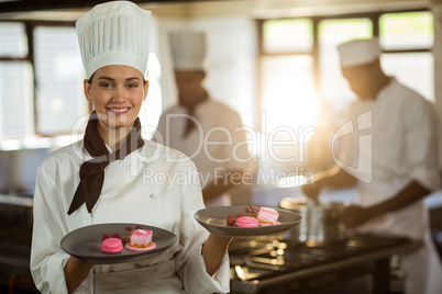 Portrait of smiling female chef presenting dessert plates