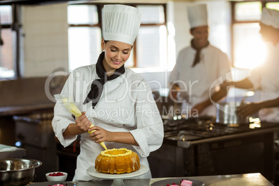 Female chef piping icing on cake
