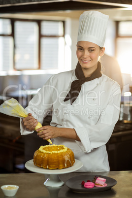 Portrait of female chef piping icing on cake