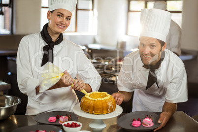 Portrait of two chefs preparing a cake