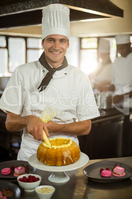 Portrait of smiling chef piping icing on cake