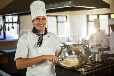 Portrait of smiling chef mixing dough