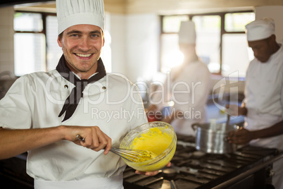 Portrait of smiling chef mixing dough