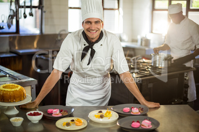 Portrait of smiling chef presenting dessert plates