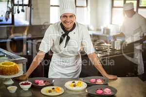 Portrait of smiling chef presenting dessert plates