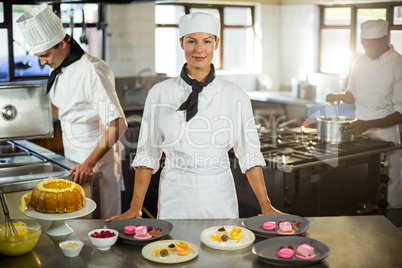 Portrait of female chef presenting dessert plates