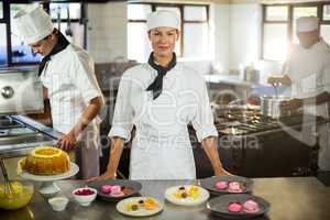 Portrait of female chef presenting dessert plates