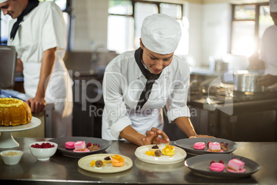 Smiling female chef finishing dessert plates