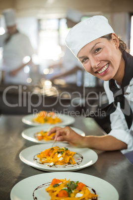 Portrait of female chef garnishing plate of food