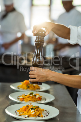 Chef sprinkling pepper on a meal