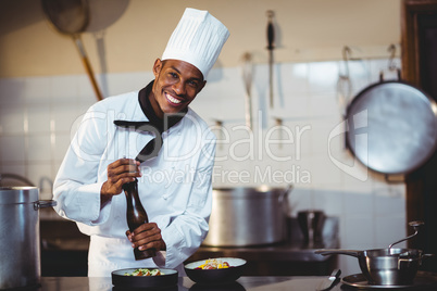 Portrait of chef sprinkling pepper on a meal
