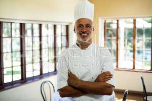 Portrait of smiling chef standing with arms crossed