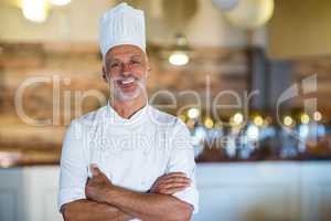 Portrait of smiling chef standing with arms crossed