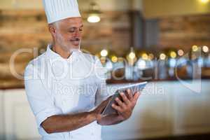 Smiling chef using digital tablet
