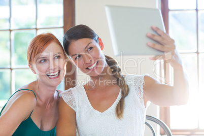 Two beautiful women taking selfie with digital tablet