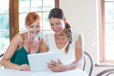 Two smiling women using a digital tablet