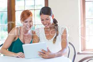 Two smiling women using a digital tablet