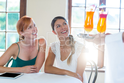 Waiter serving cocktail to women in restaurant