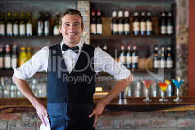 Portrait of confident waiter standing with hands on hip