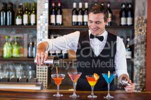 Bartender pouring a orange martini drink in the glass