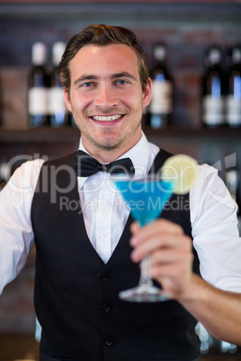 Portrait of bartender serving a blue martini