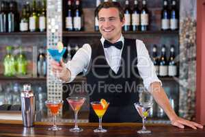 Happy bartender serving a blue martini