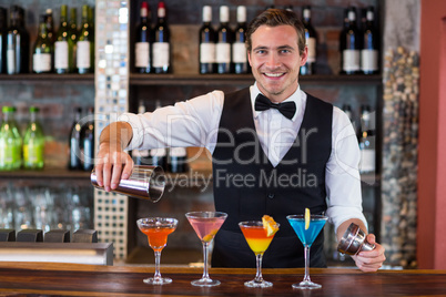 Portrait of bartender pouring a orange martini drink in the glass