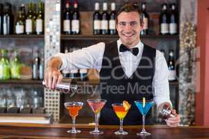 Portrait of bartender pouring a orange martini drink in the glass
