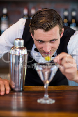 Bartender garnishing cocktail with olive