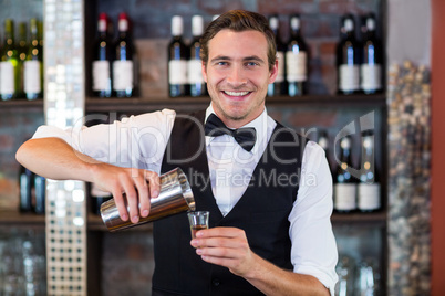 Portrait of bartender pouring tequila into shot glass