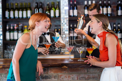 Friends standing at counter while bartender preparing a drink