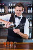 Bartender pouring tequila into shot glasses