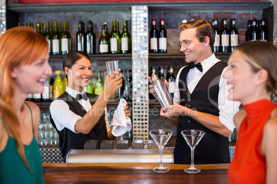 Friends standing at counter while bartender preparing a drink