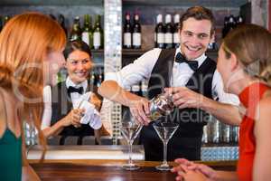 Friends standing at counter while bartender preparing a drink